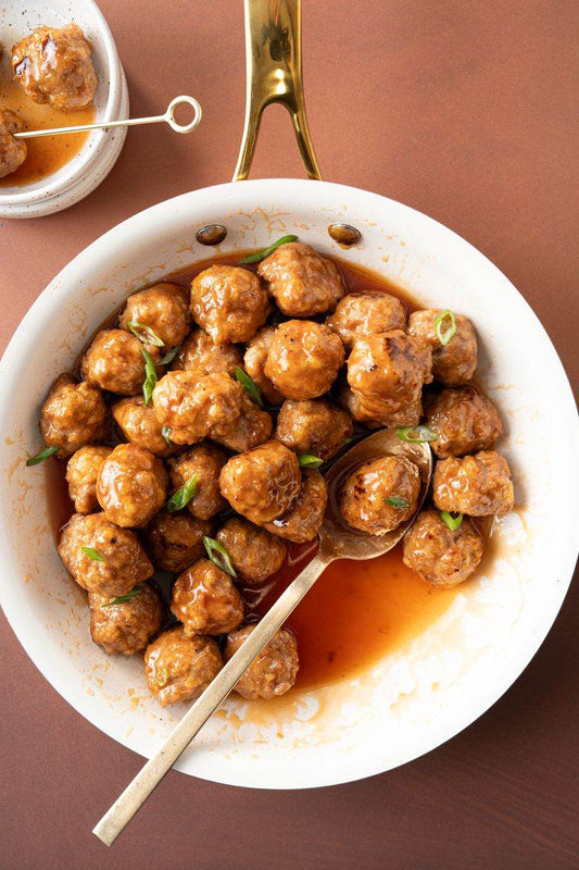 Hot honey Turkey Meatballs in a white pan with a spoon.