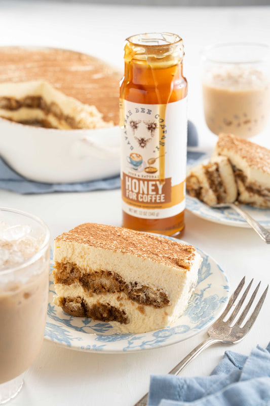 A slice of tiramisu next to a jar of honey for coffee.