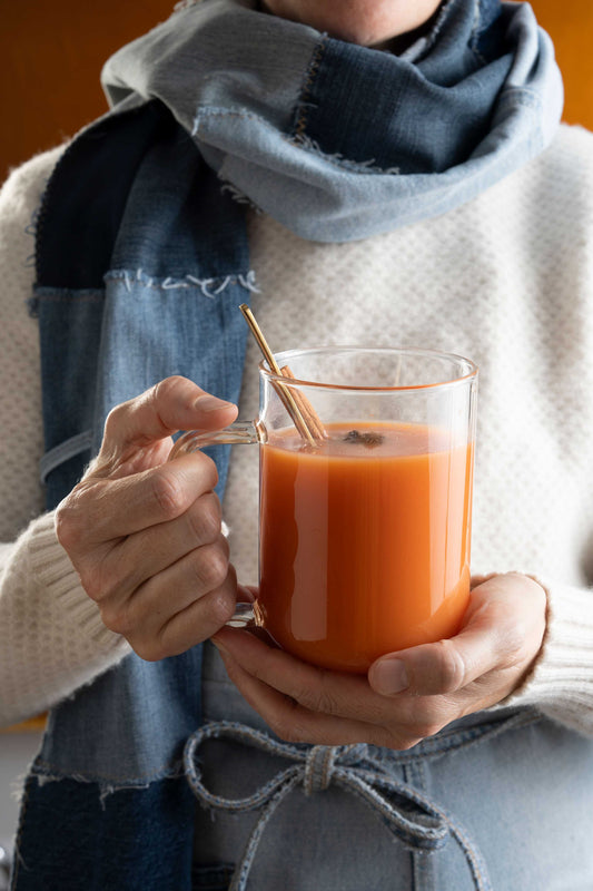 Blood orange hot toddy held by a lady in denim.