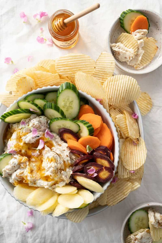 Onion dip and raw vegetables in a bowl with potato chips.