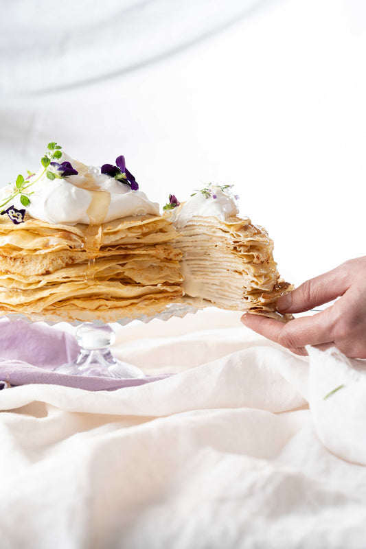 Hand revealing layers of a honey lavender crepe cake.
