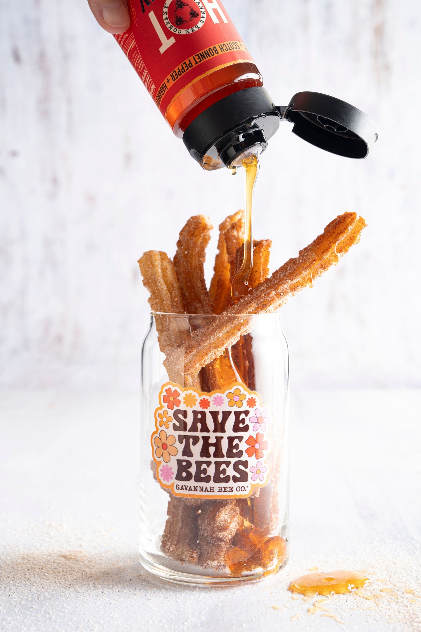 Save the bees glass can filled with churros being drizzled with hot honey