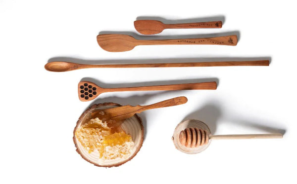 Wooden honey utensils. Wooden honeycomb knife is on top raw honeycomb. Utensils are used for scrooping out honey and drizzling it over coffee, tea or food.