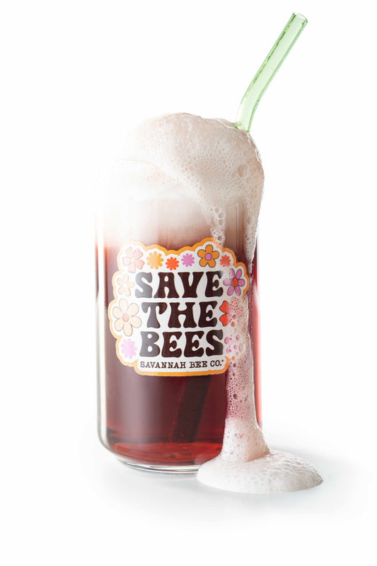 Save the bees glass with a green glass straw filled with mead and foam at the top