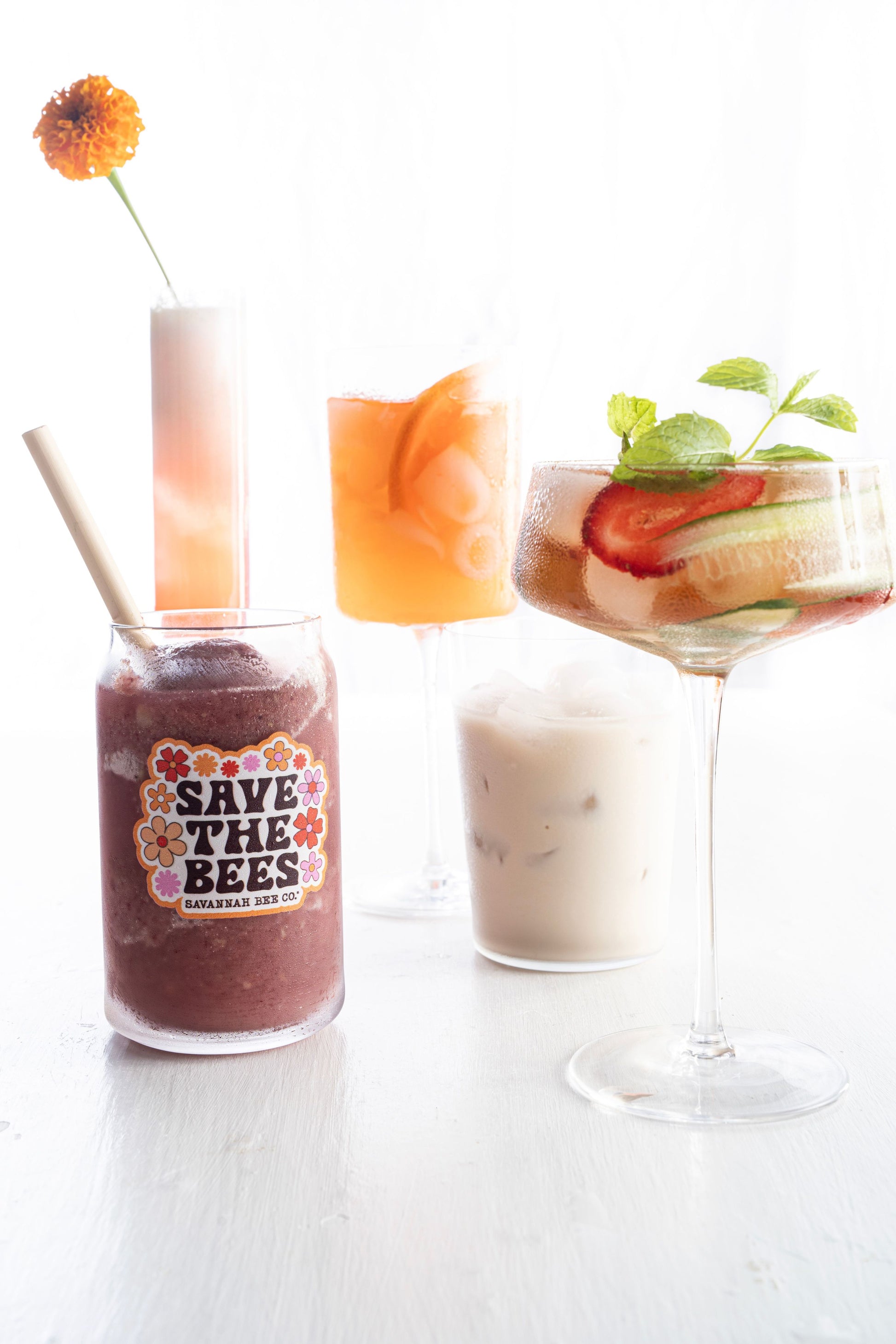 Save the bees glass can with a blended daiquiri surrounded by colorful cocktails