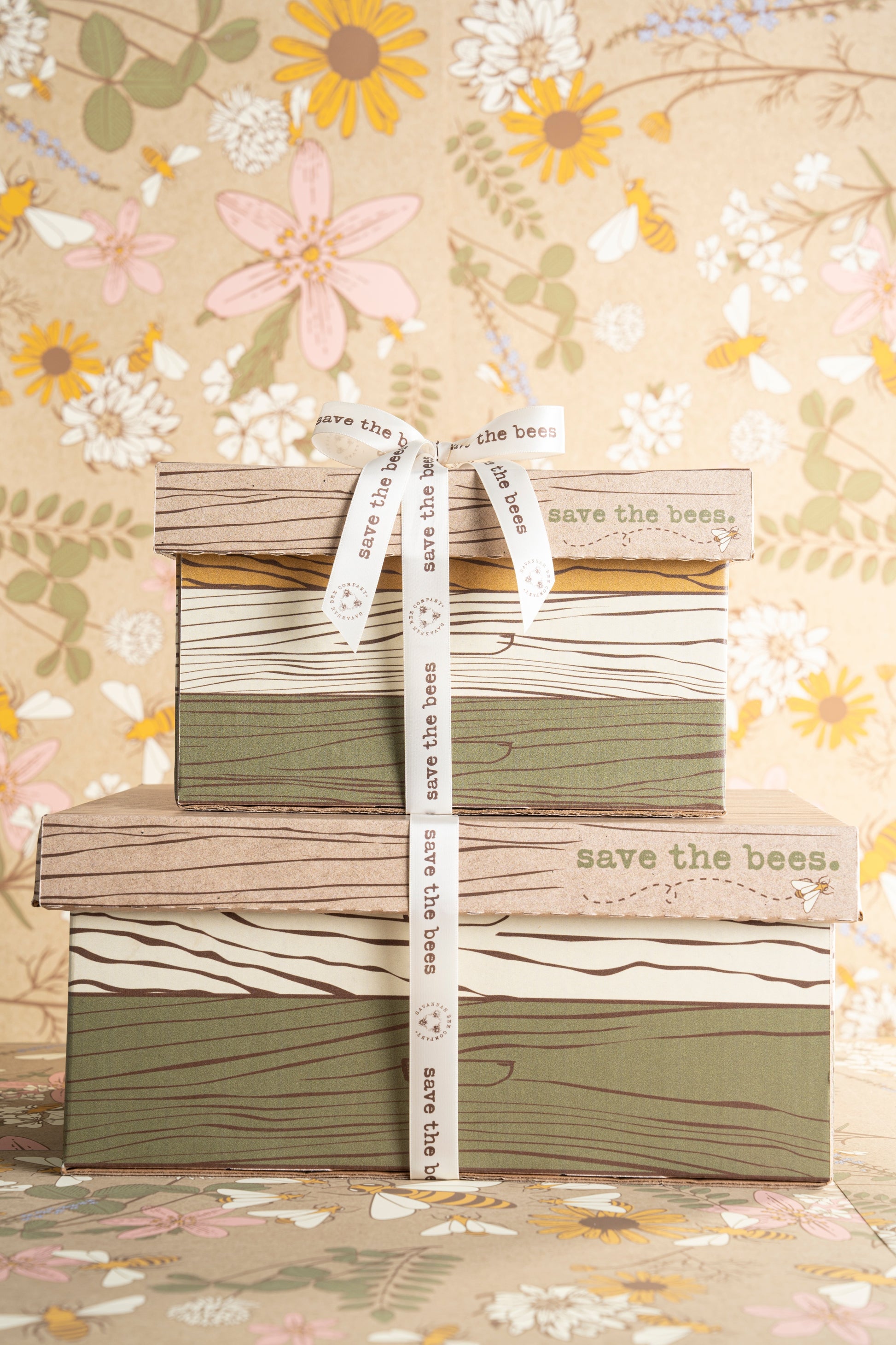 One small and one large gift boxes stacked with a save the bees ribbon tied around them