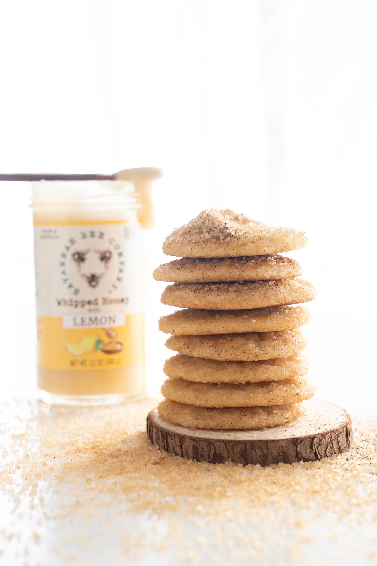 A stack of lemon clove cookies next to a jar of whipped honey with lemon.