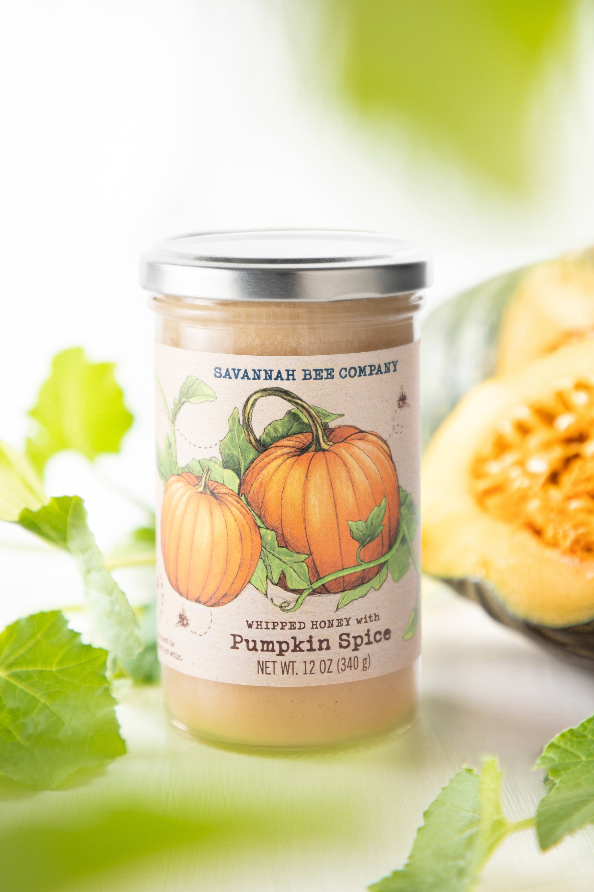 12 ounce pumpkin spice whipped honey next to pumpkins and pumpkin vines.