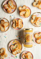 Butterfly shaped cookies on small plates with multicolored sprinkles next to a 12 ounce jar of sunflower honey.