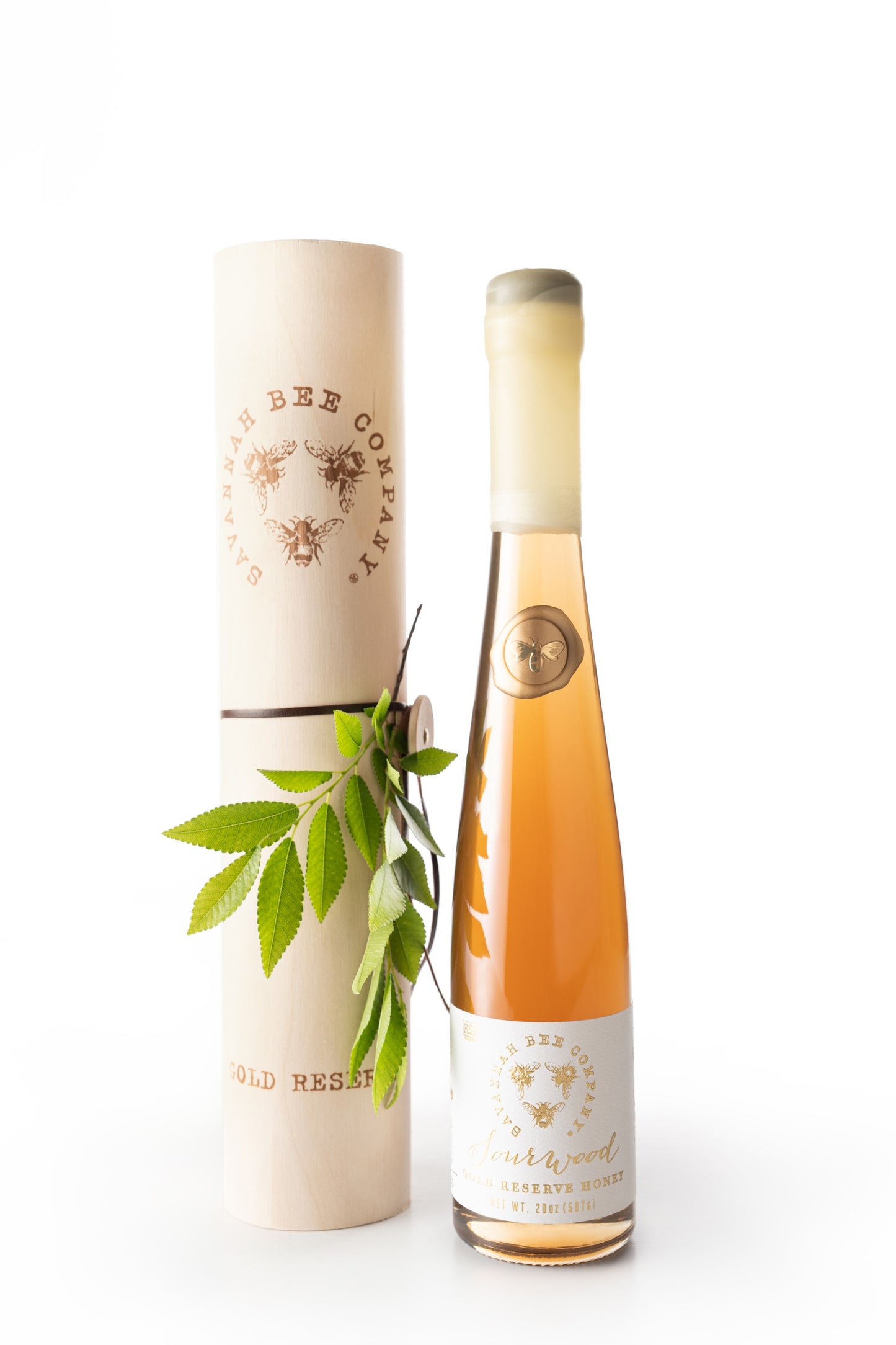 20 ounce Sourwood gold reserve honey flute with decorative box and a sprig of green leaves.