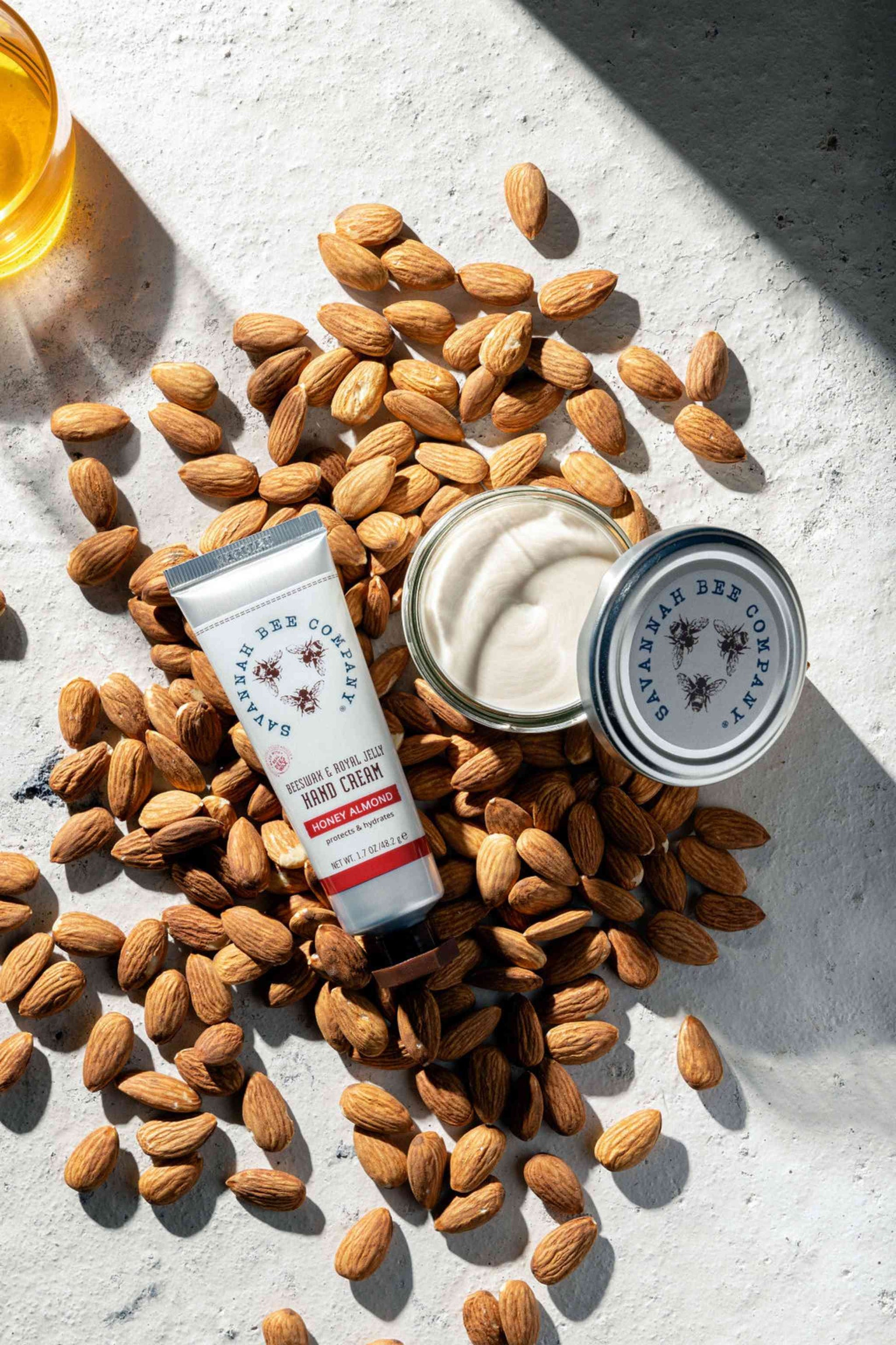 Honey Almond Beeswax & Royal Jelly Hand cream in a Jar or Tube on a pile of almonds.