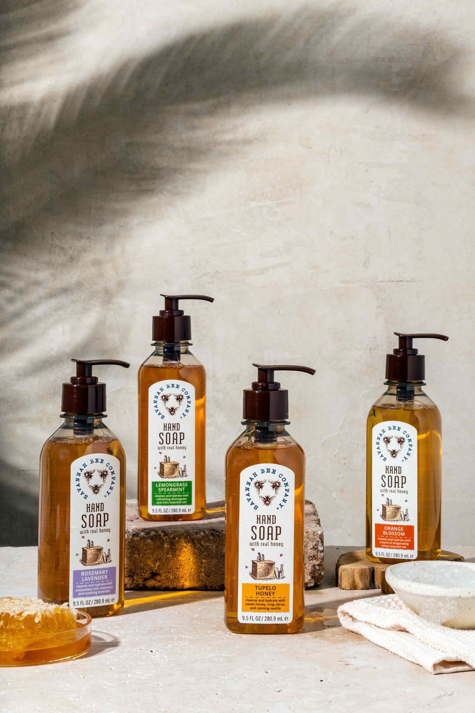 Rosemary Lavender, Lemongrass Spearmint, Tupelo Honey and Orange Blossom Hand Soap next to honeycomb.