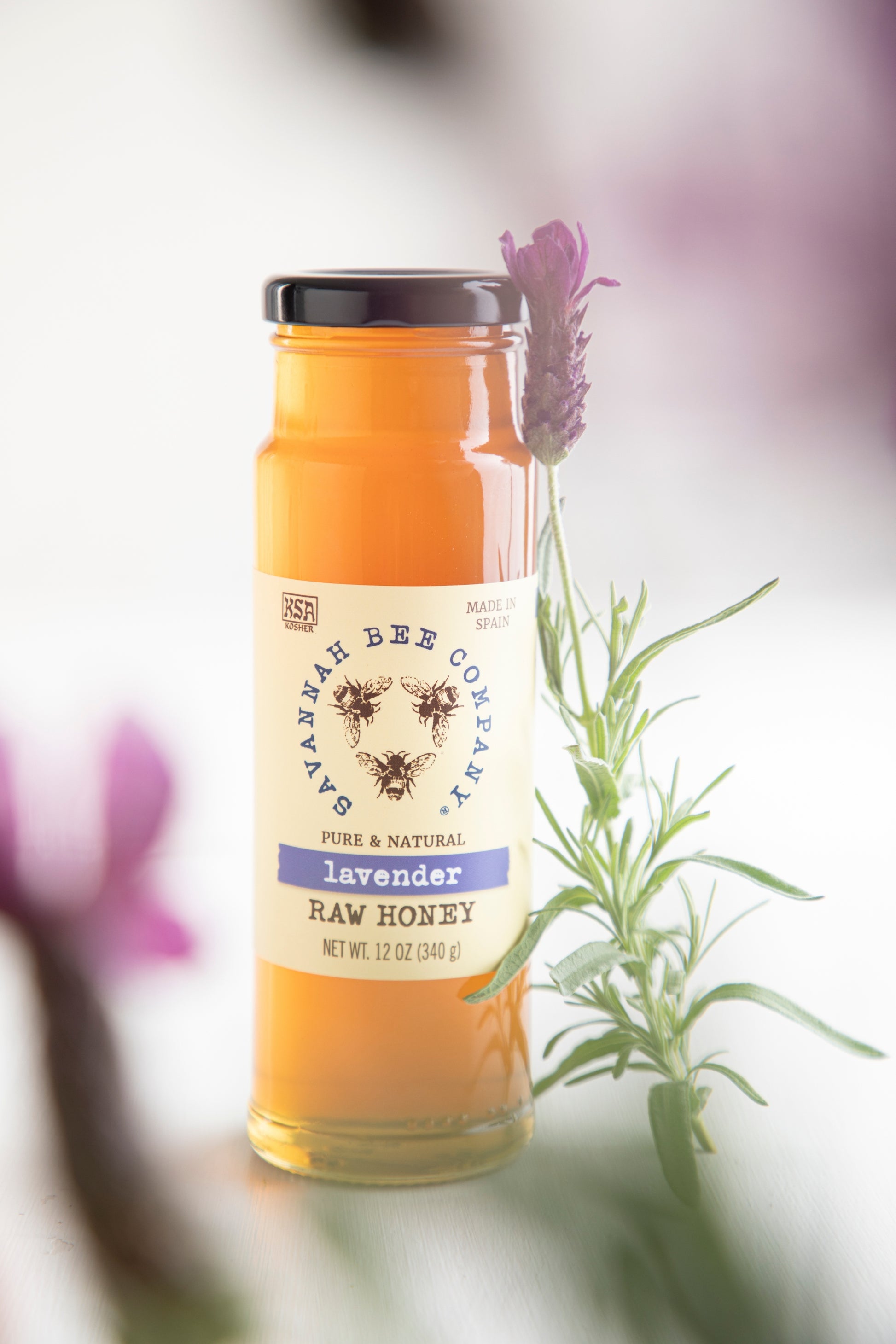 Pure & Natural Lavender Raw Honey 12 oz. surrounded by lavender sprigs.