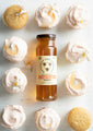 Orange blossom cupcakes with pink frosting surrounding 12 ounce jar of orange blossom honey.