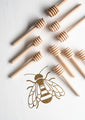Ten mini honey dippers against a white background with a gold bee.