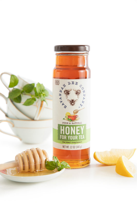 Honey for Tea, the ideal complement 12 oz. tower next to tea cups and some lemon slices.
