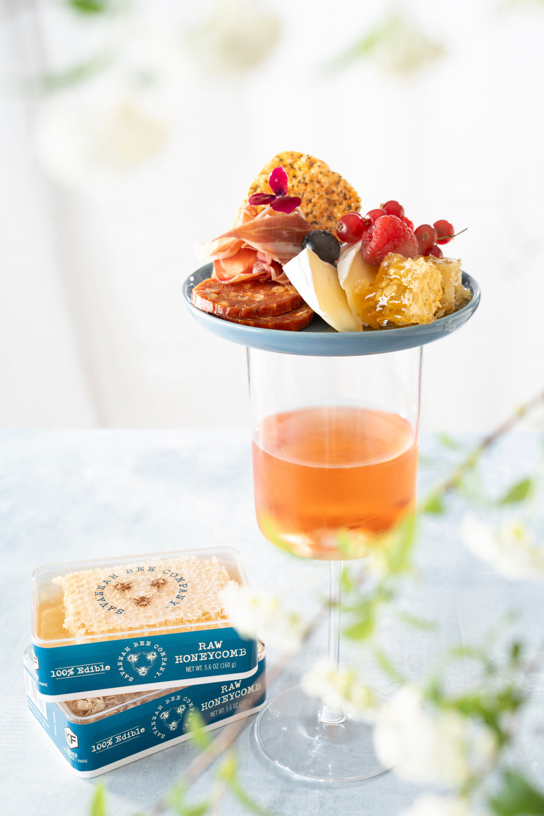 Charcuterie Plate on a glass of wine next to two packs of honey.