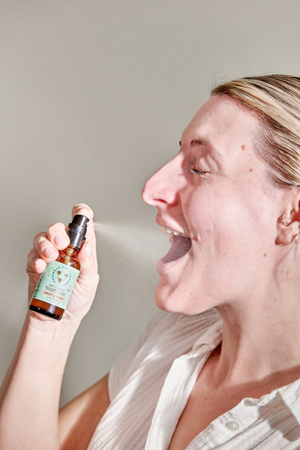 Woman spraying propolis into her mouth.
