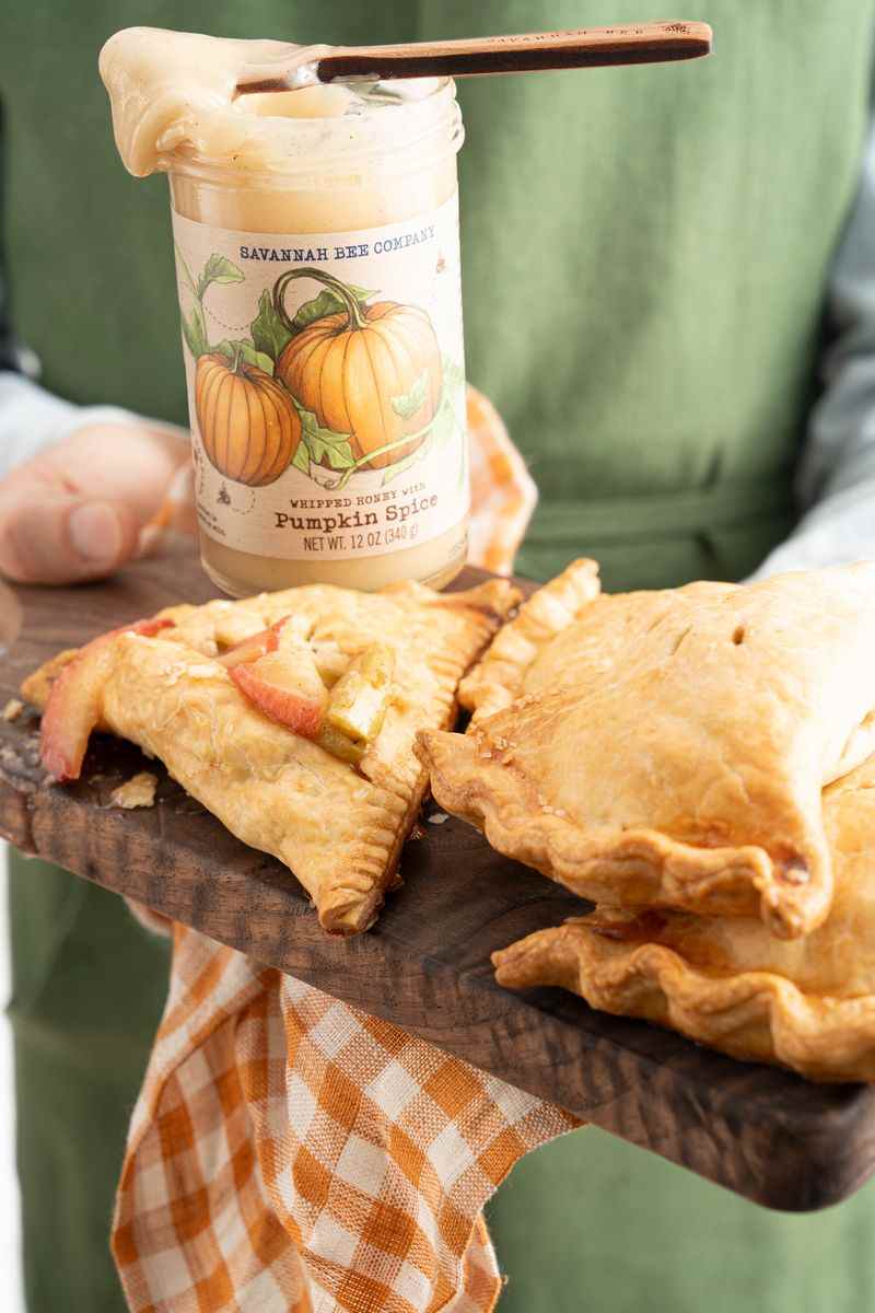 Hand pies with pumpkin spice honey on a serving board. 