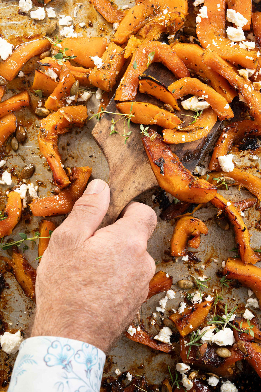 Pumpkin spice roasted pumpkin with herbs and feta on a pan.