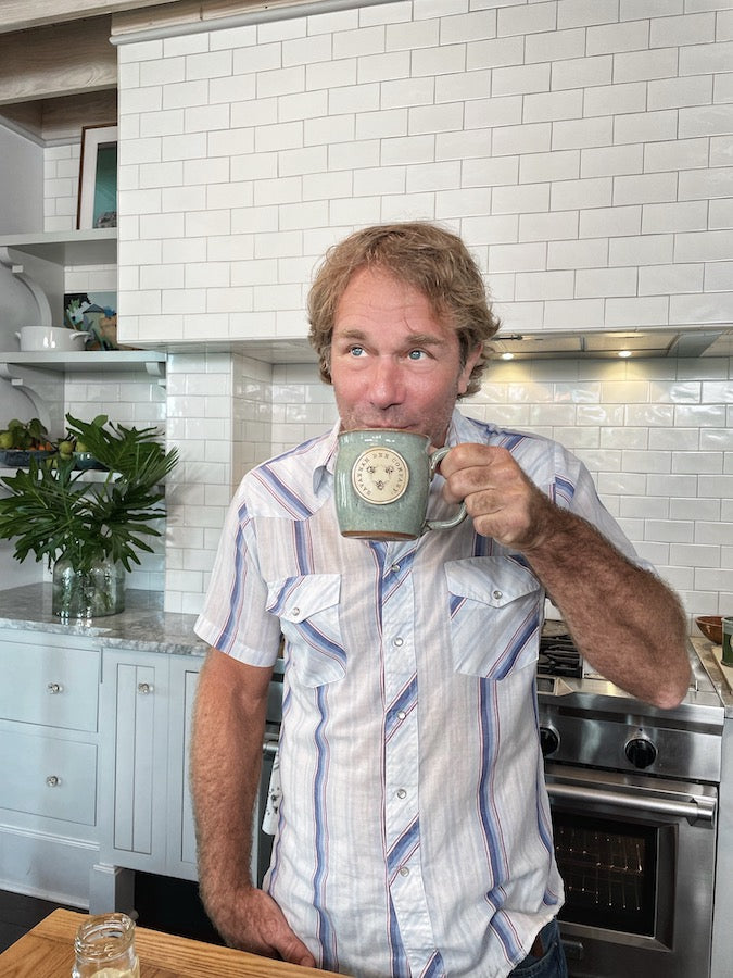 Savannah Bee Company founder Ted Dennard drinking from the robin's egg Handcrafted stoneware mug with Savannah Bee Company logo on the front 