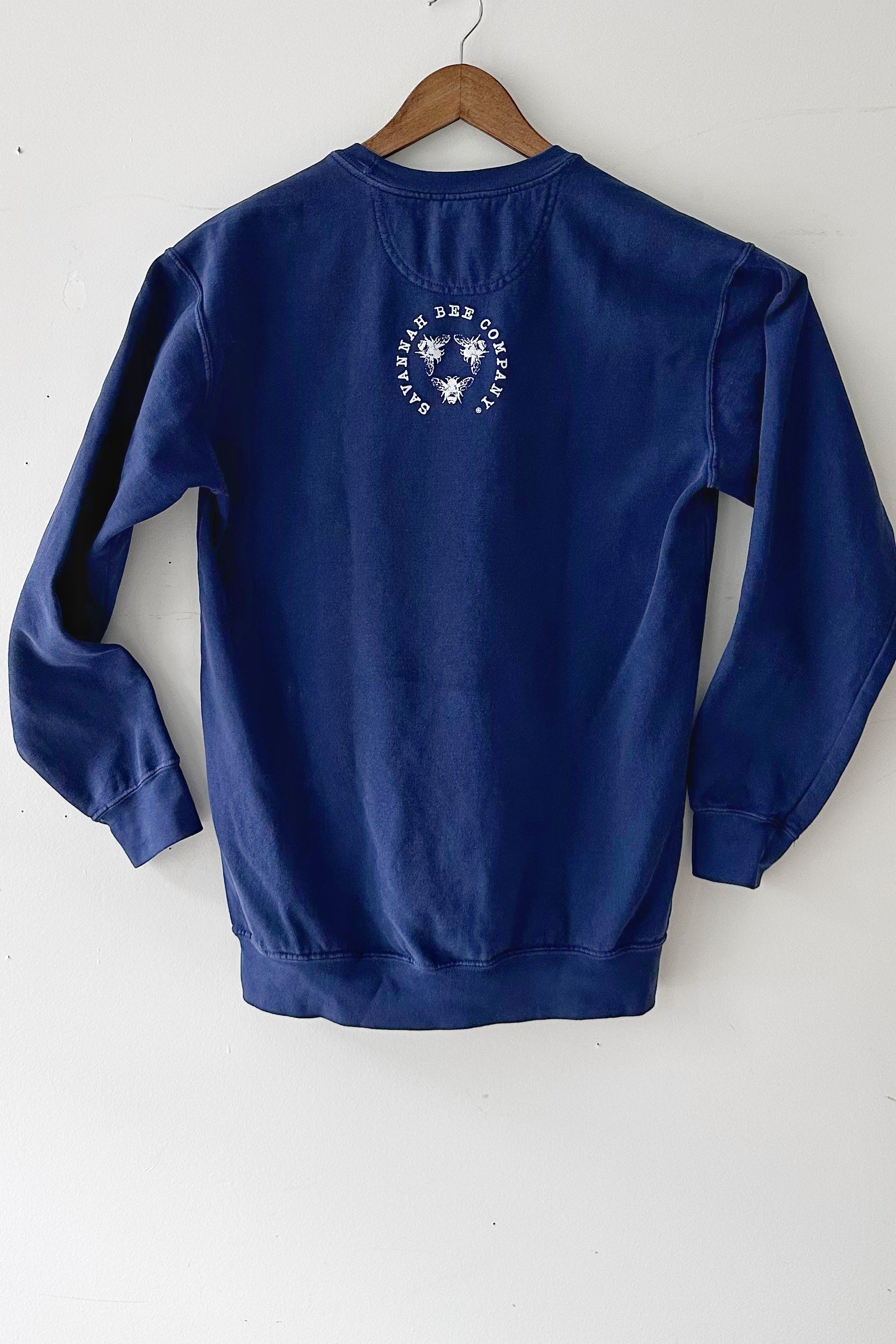 Navy blue varsity sweatshirt from behind with the Savannah Bee Company logo hanging against a white background.