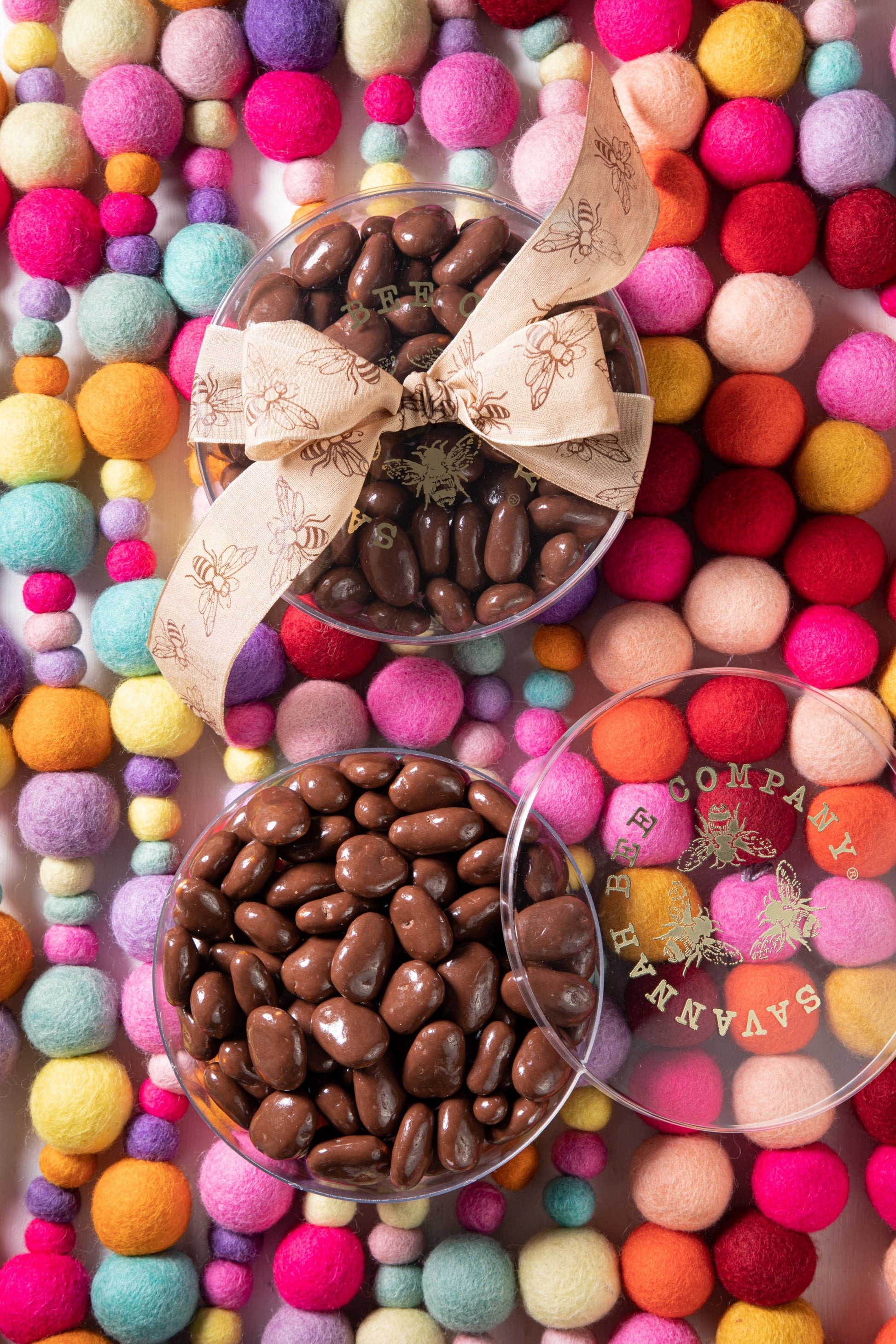 Chocolate covered honey crisp pecans in a container on a multicolored background.