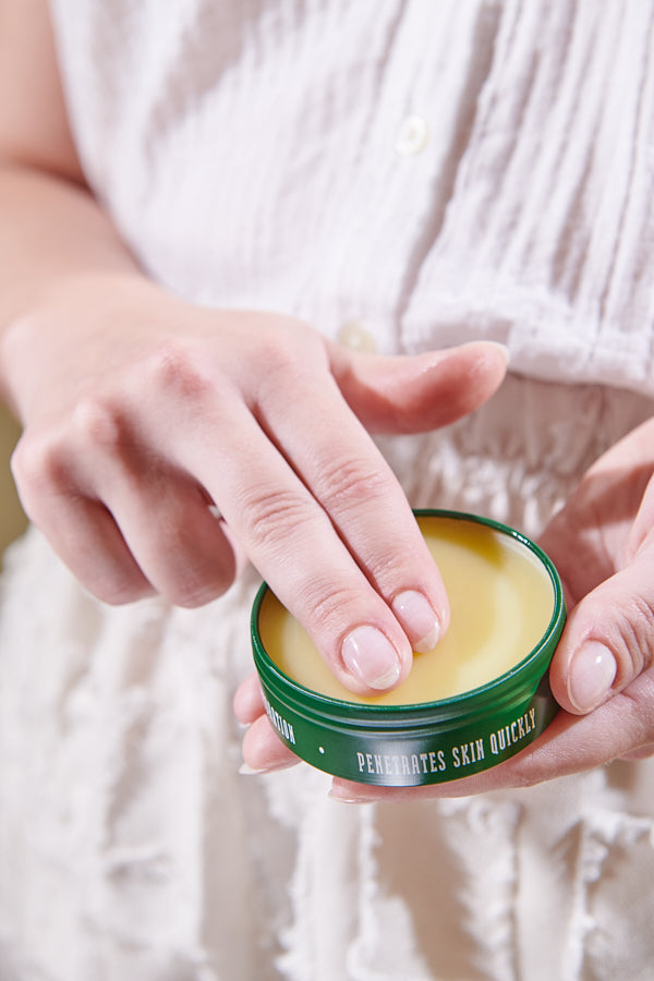 Two fingers going into the spearmint beeswax salve