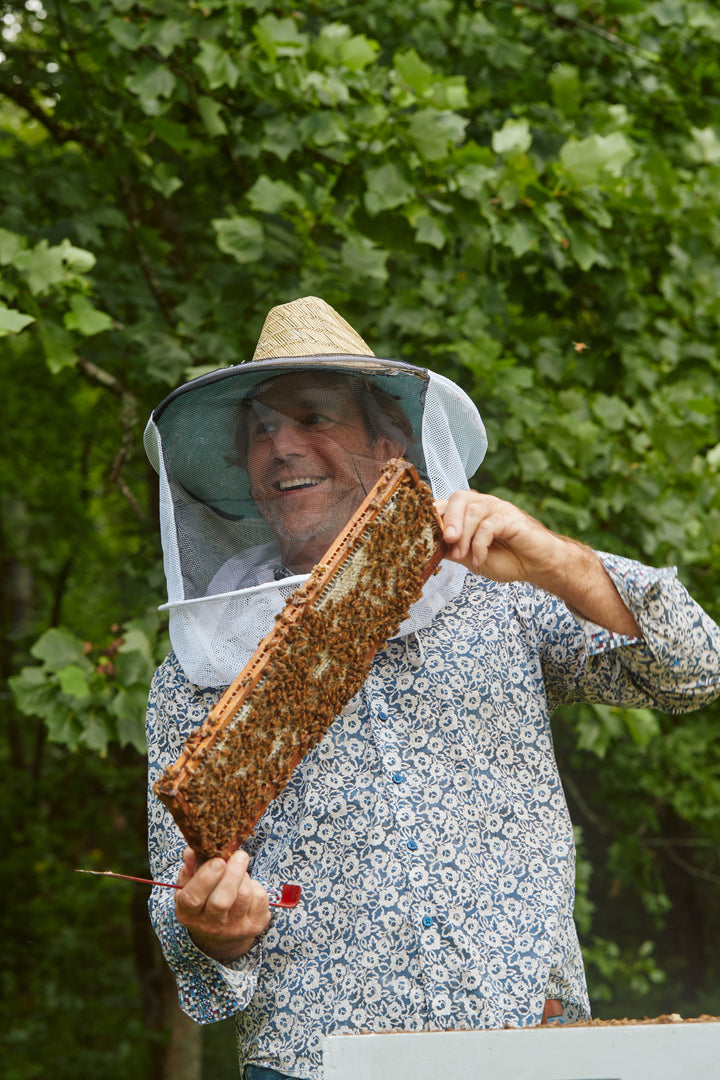 A Savannah Bee beekeeper holding a honeycomb frame
