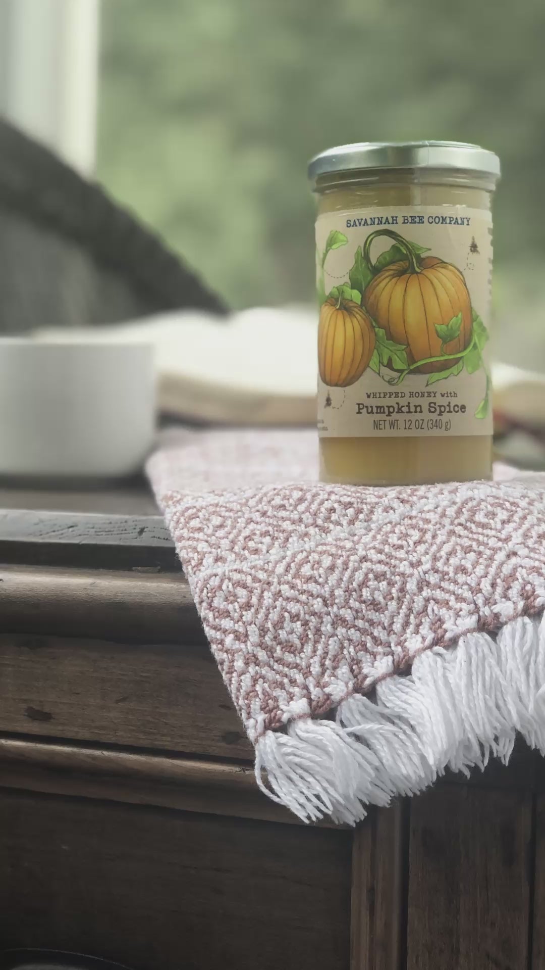 Pumpkin spice whipped honey on a brown wooden counter with a steaming cup of tea.