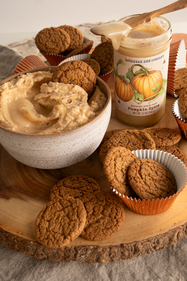 Cookies and a bowl of pumpkin spice cannoli dip next to an open 12 ounce jar of pumpkin spice whipped honey.