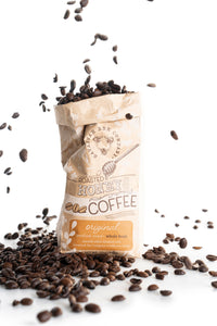 Whole bean roasted honey coffee bag surrounded by beans
