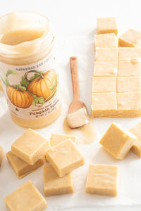 A block and a few squares of pumpkin spice whipped honey fudge next to a 12 ounce jar of pumpkin spice whipped honey