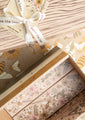 One opened gift box with floral pattern on the inside next to a closed gift box tied with a save the bees ribbon