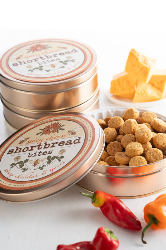 Spicy cheese shortbread cookie bites. Surround by cheese and pepper's in a floral metal tin.