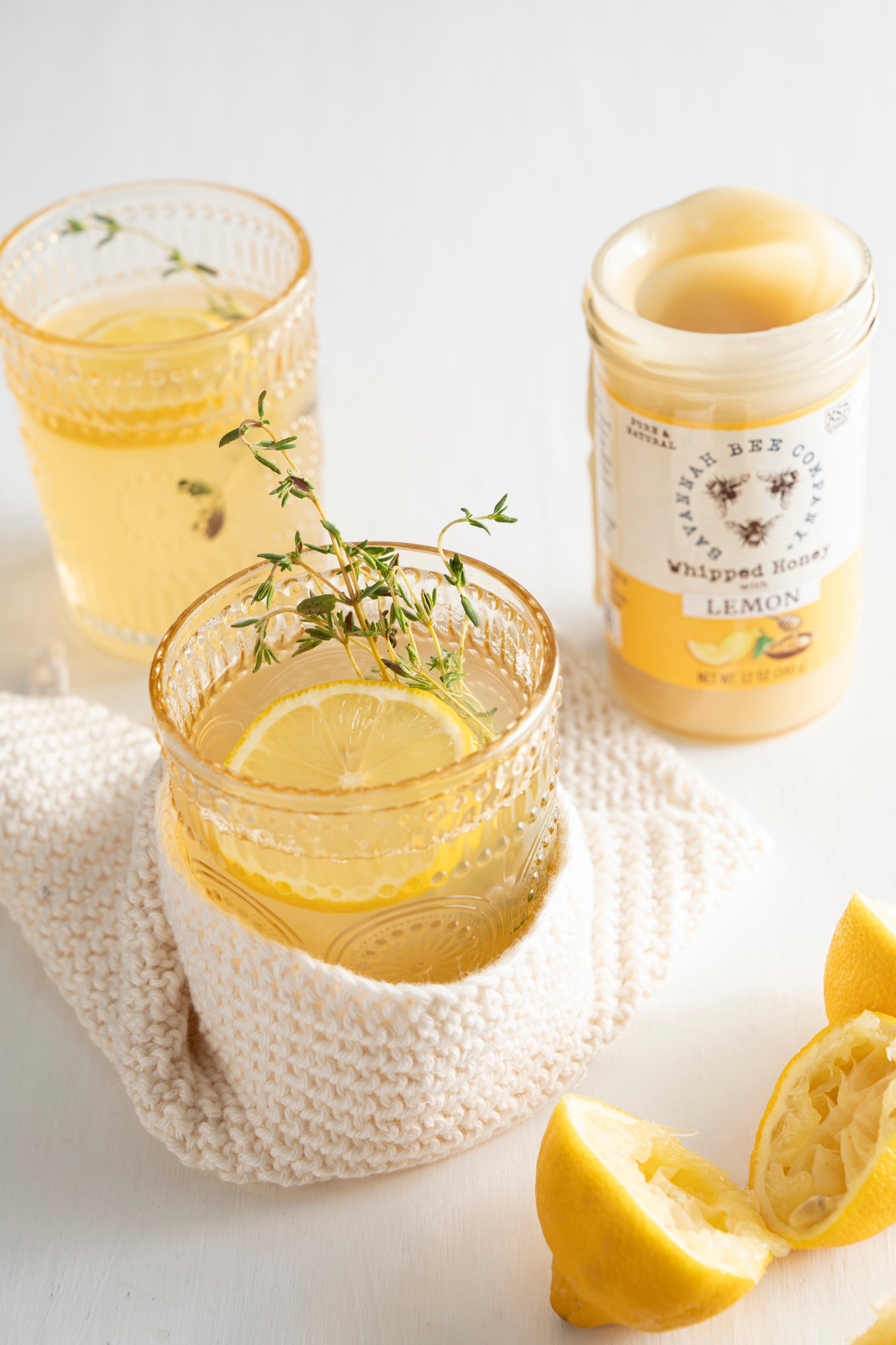 Whipped Honey with lemon next to a lemon toddy with lemon slice and a sprig.