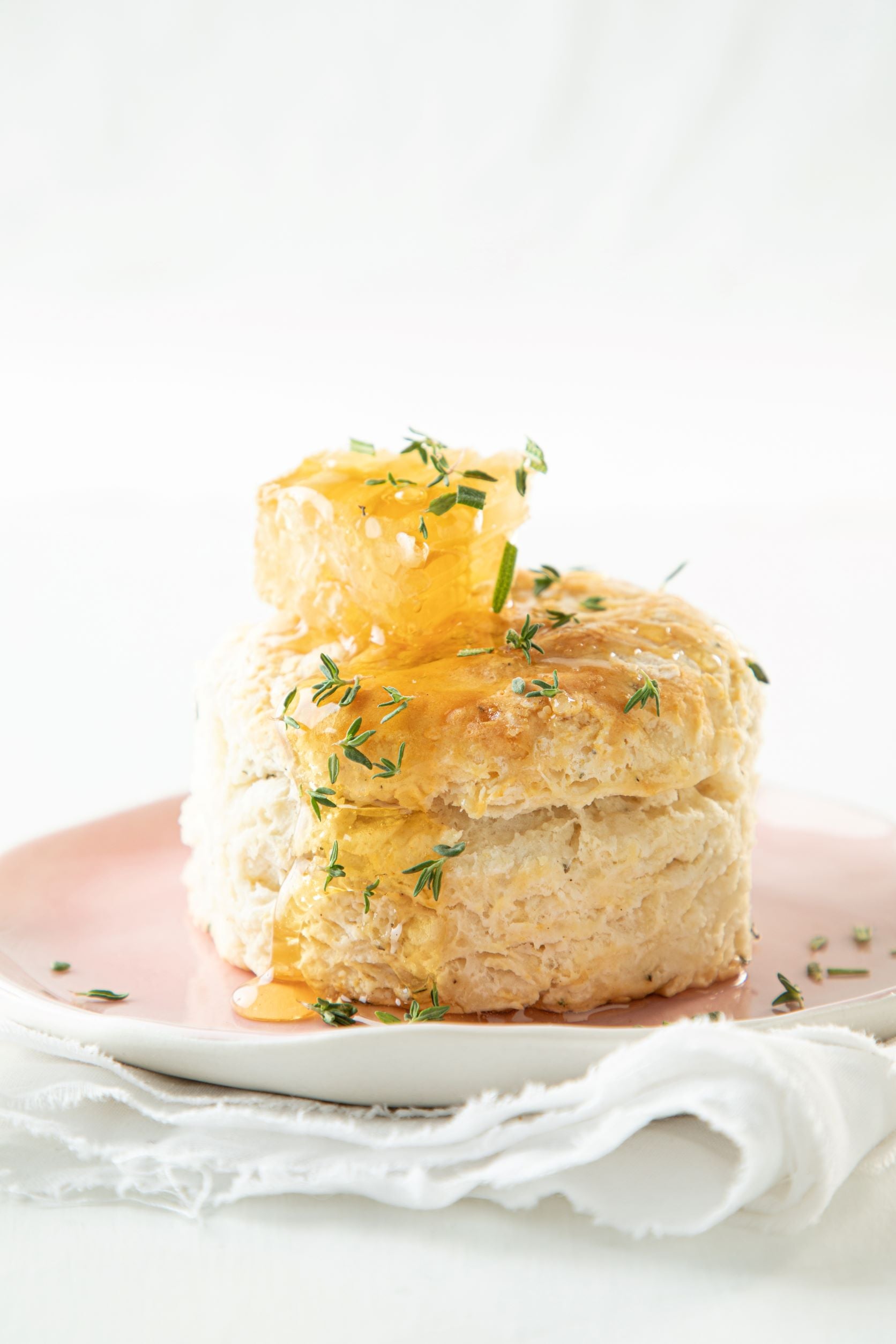 Homemade biscuit plated and toped with raw honeycomb and sprinkled with fresh rosemary. 