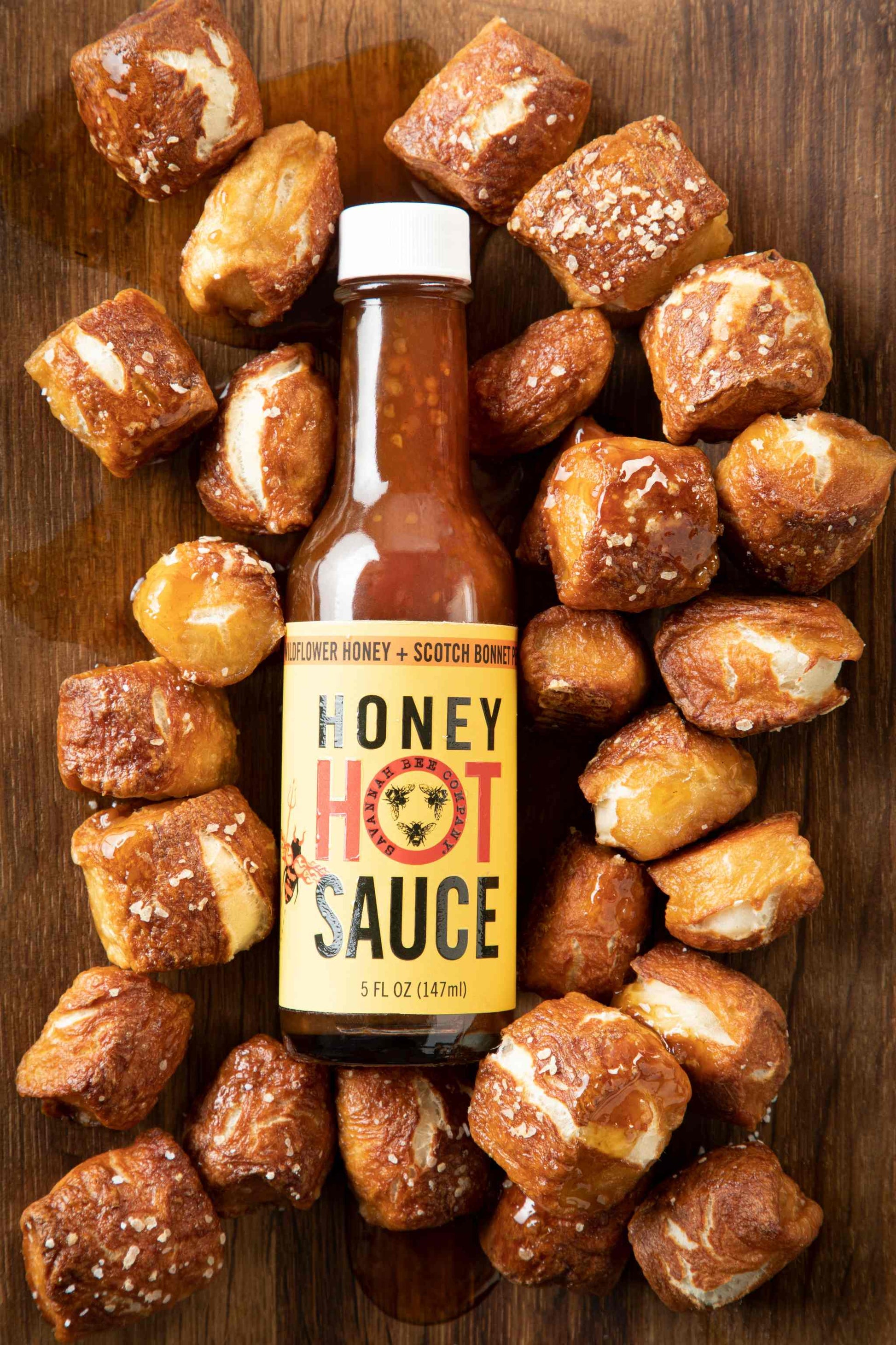 Honey hot sauce surrounded by pretzel bites on a table