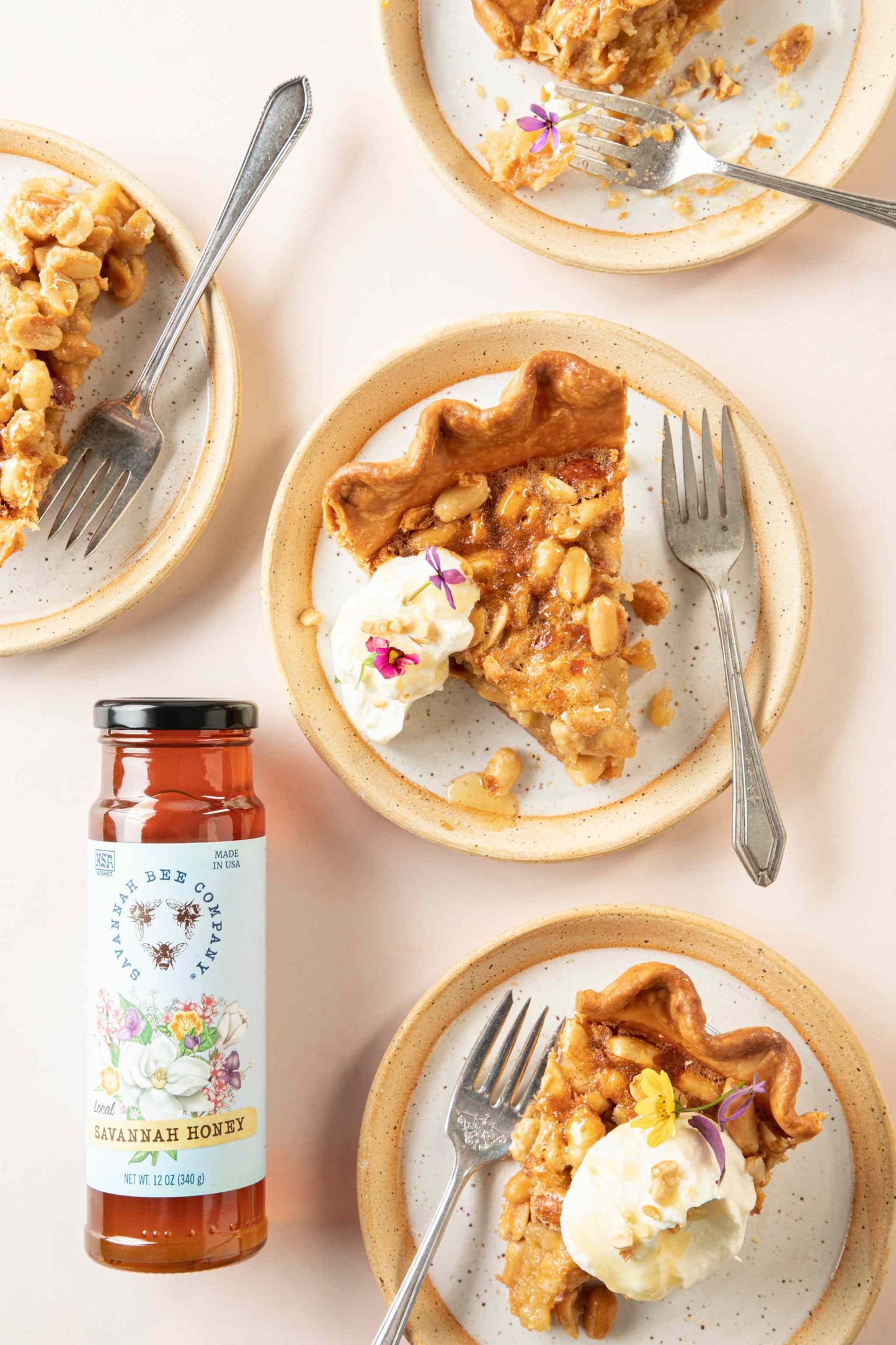Four plates of sliced peanut pie with whipped cream next to a jar of Savannah Honey 12 ounce.